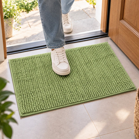 A person's feet in white sneakers stepping onto a bright green bobble mat placed on a tiled floor near a doorway.
