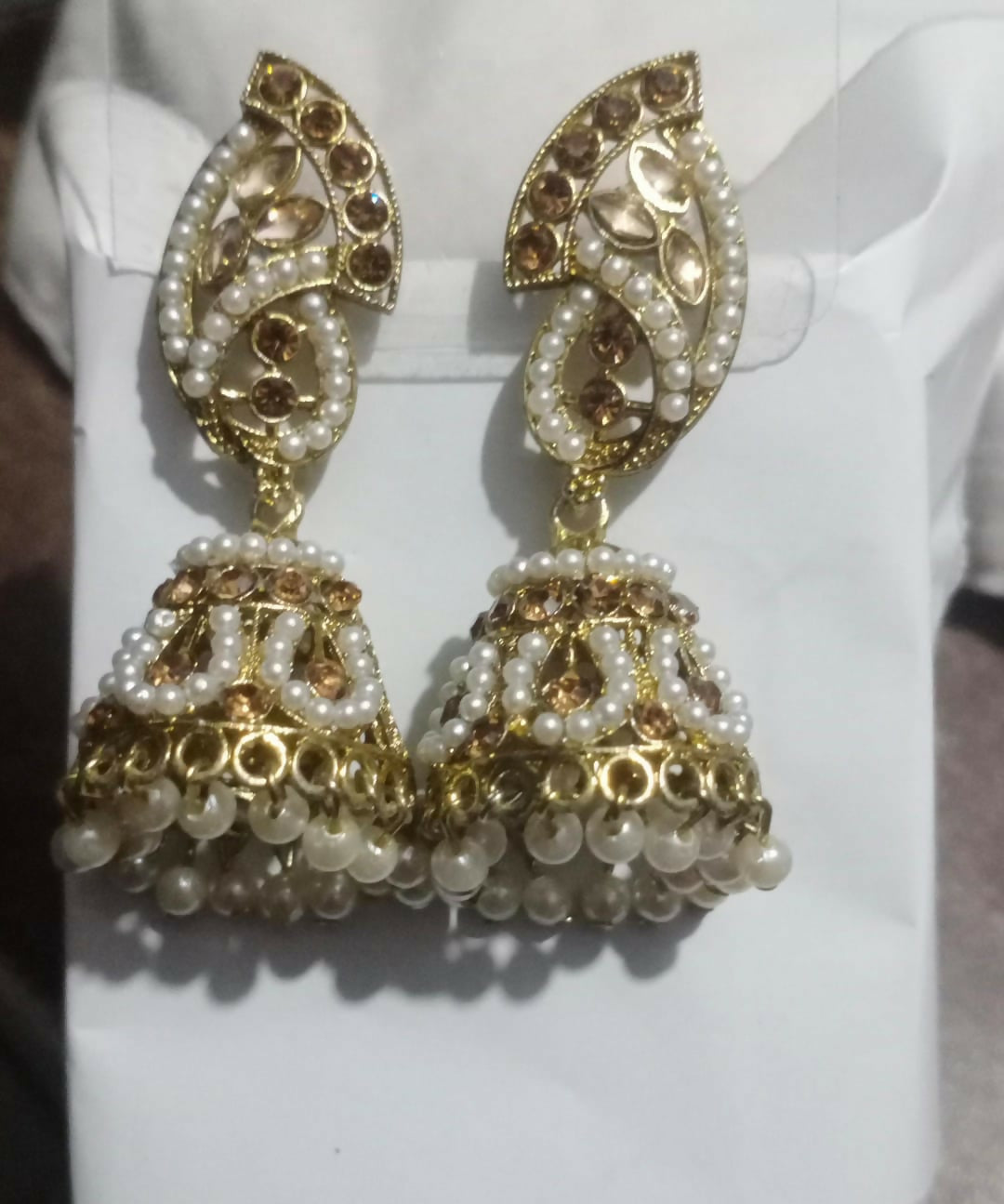 Model wearing gold plated pearl and stone jhumka earrings