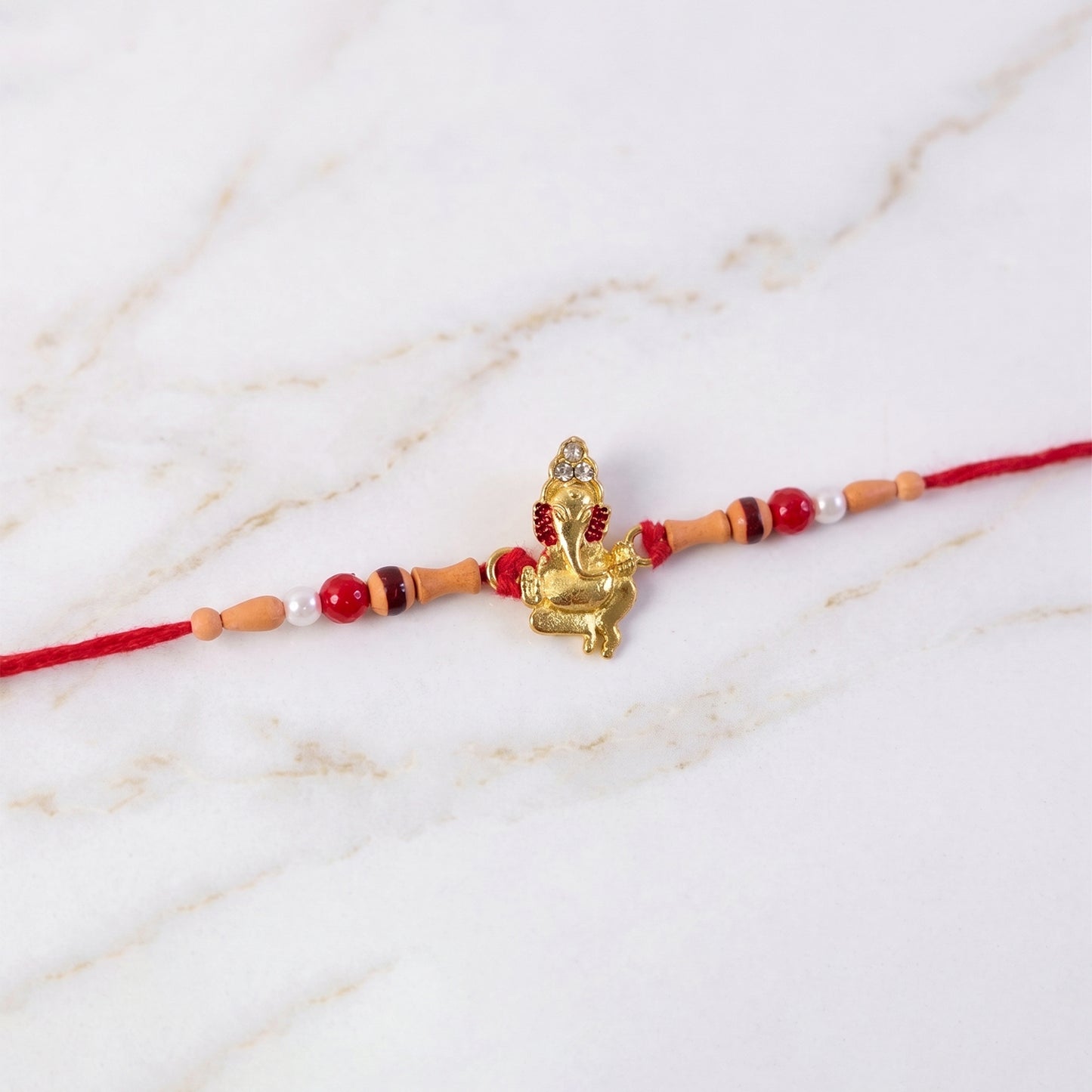 Golden Ganesha Rakhi with Peach Beads and Pearl Accents
