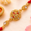 Gold-Toned Trishul Rakhi with Red Stones, Clear Crystal Accents & Designer Red Thread