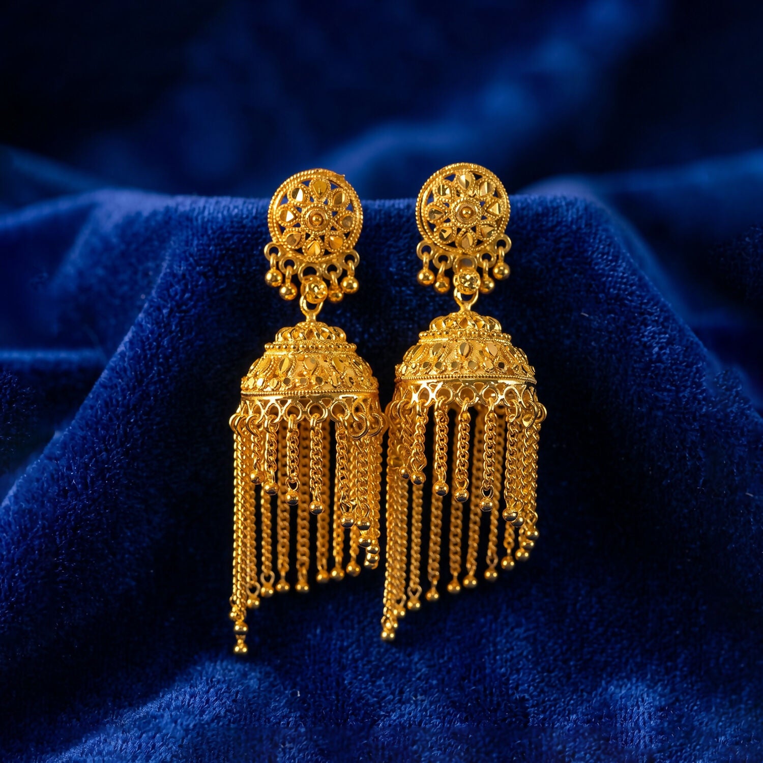 Golden tassel jhumka earrings on display stand