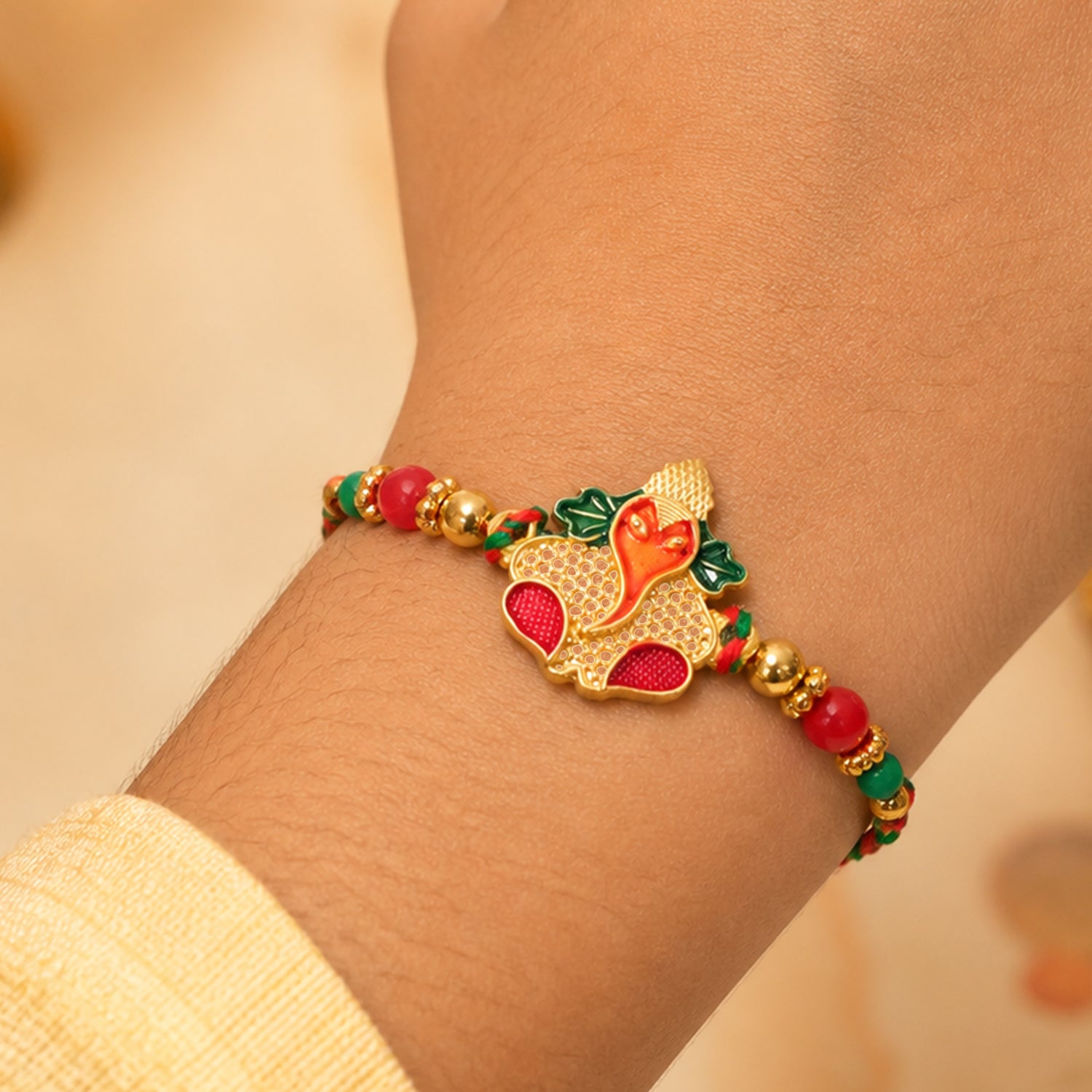 Gold Ganesha Pendant Rakhi with Red and Green Enamel