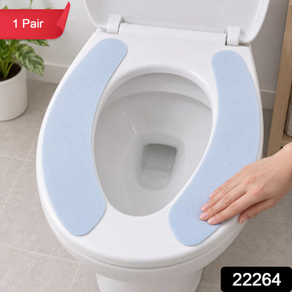 A pair of light blue toilet seat pads are placed on a white toilet, with a hand gently touching one.