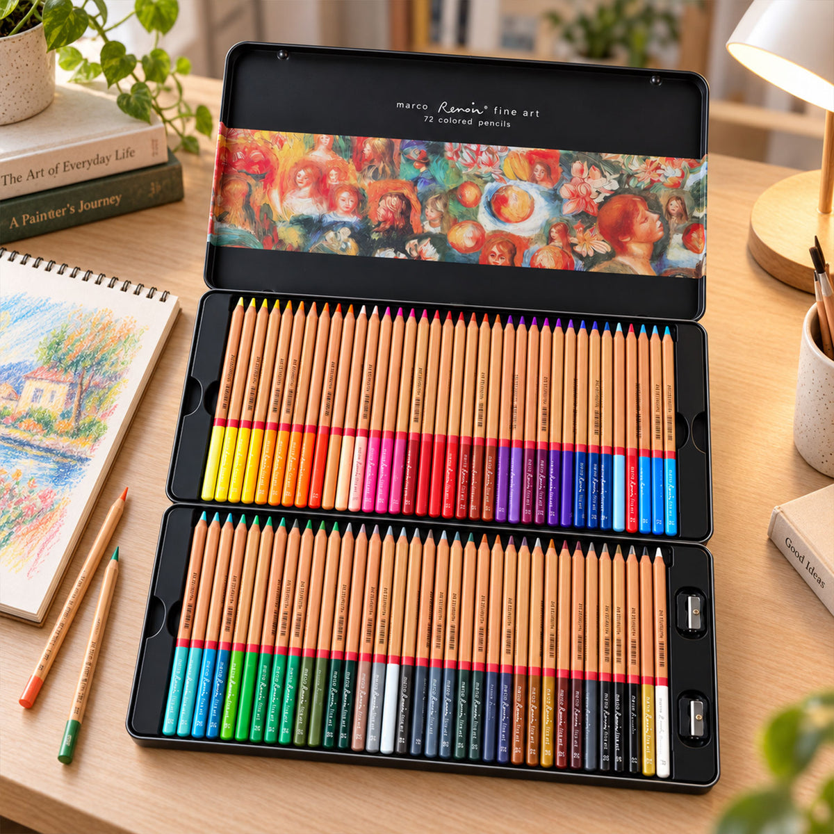An open black metal tin with 72 colored pencils and sharpeners sits on a wooden desk with art books and a drawing.