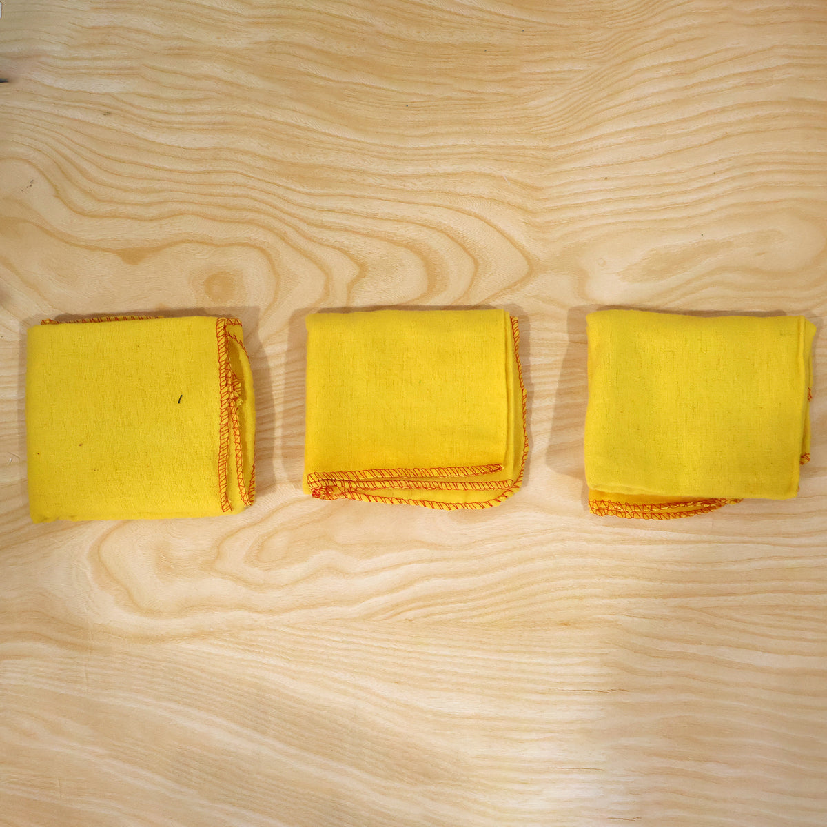 Actual photograph of three folded yellow cotton dusters