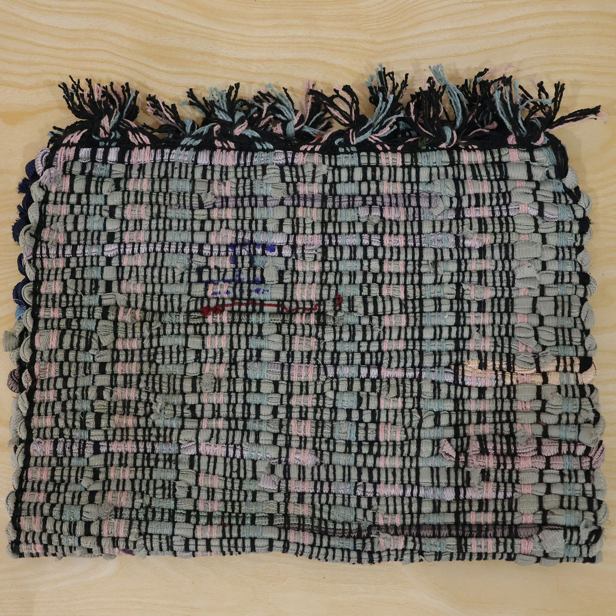 Actual photograph of woven floor mat with tassel edges