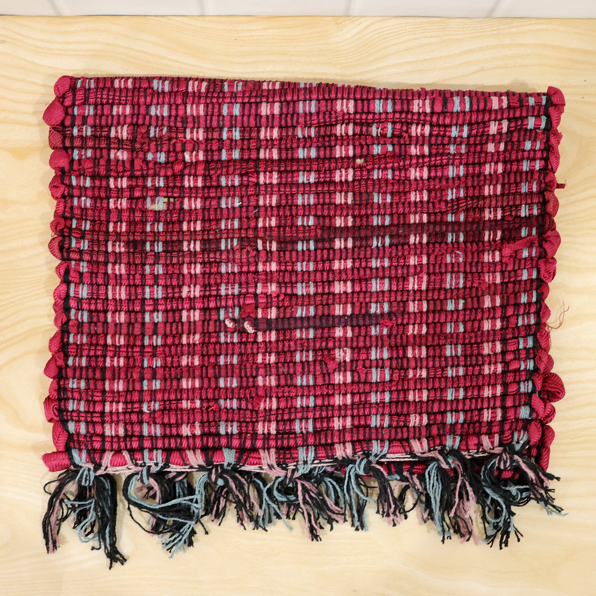 Actual photograph of woven floor mat with tassel fringe
