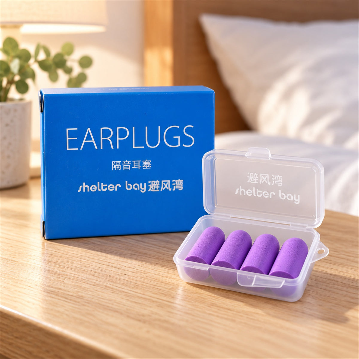 Four purple foam earplugs inside a clear plastic case next to a blue box on a wooden table.