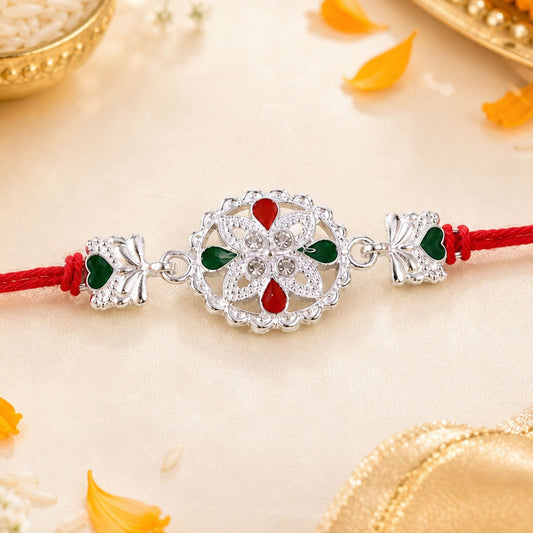 White silver floral rakhi with red stone center and side charms for Raksha Bandhan
