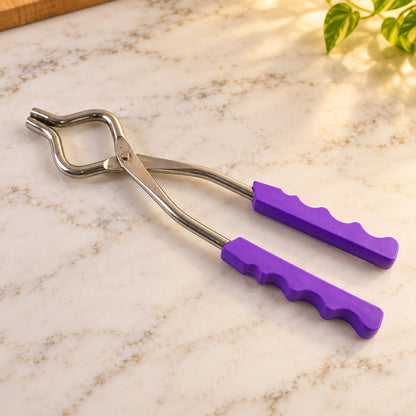 A stainless steel pot lifter with purple handles resting on a white marble countertop with soft lighting.