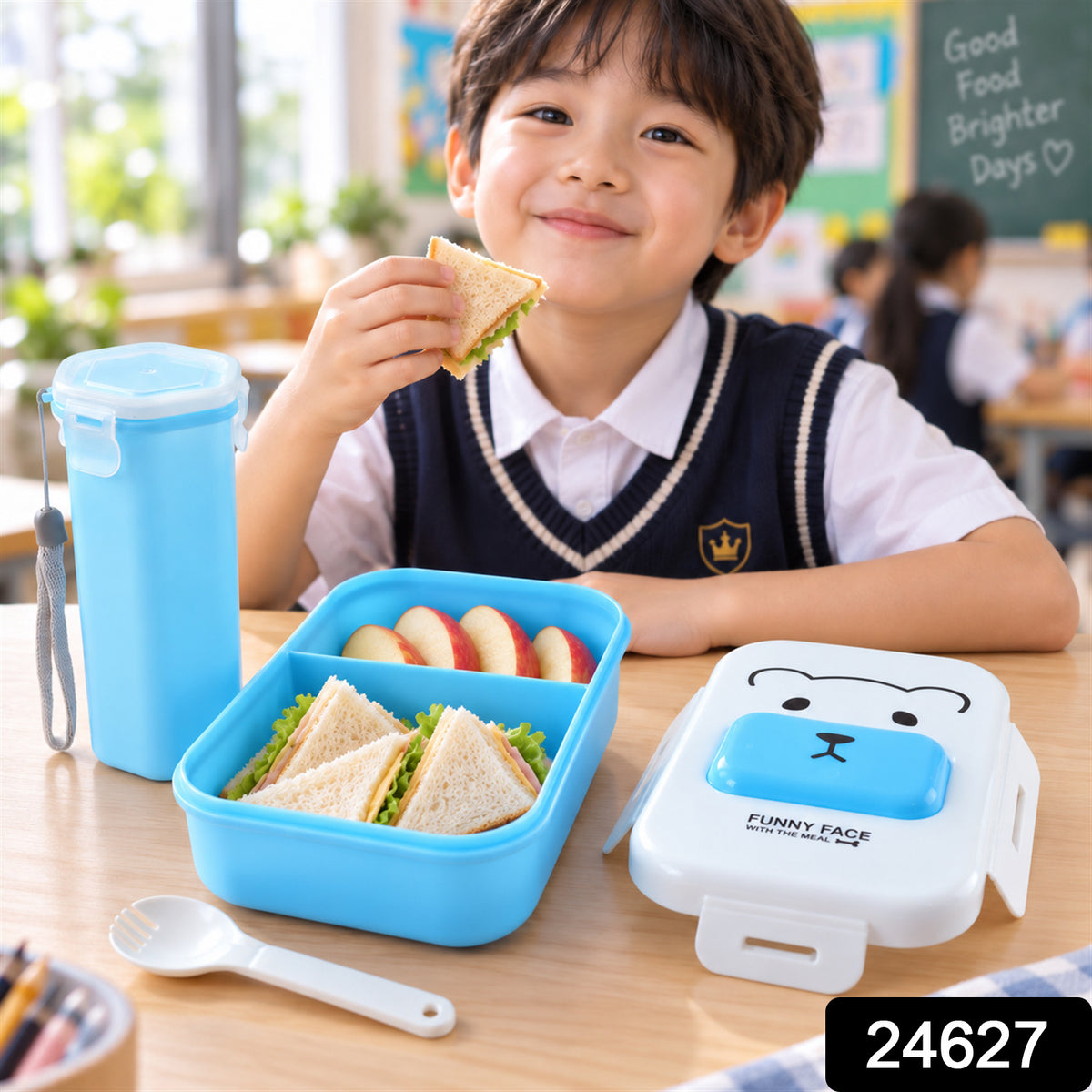 A young boy in a school uniform smiles while holding a sandwich from a blue lunchbox on a wooden table.