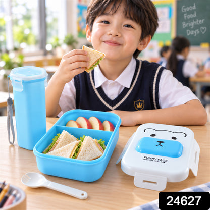A young boy in a school uniform smiles while holding a sandwich from a blue lunchbox on a wooden table.