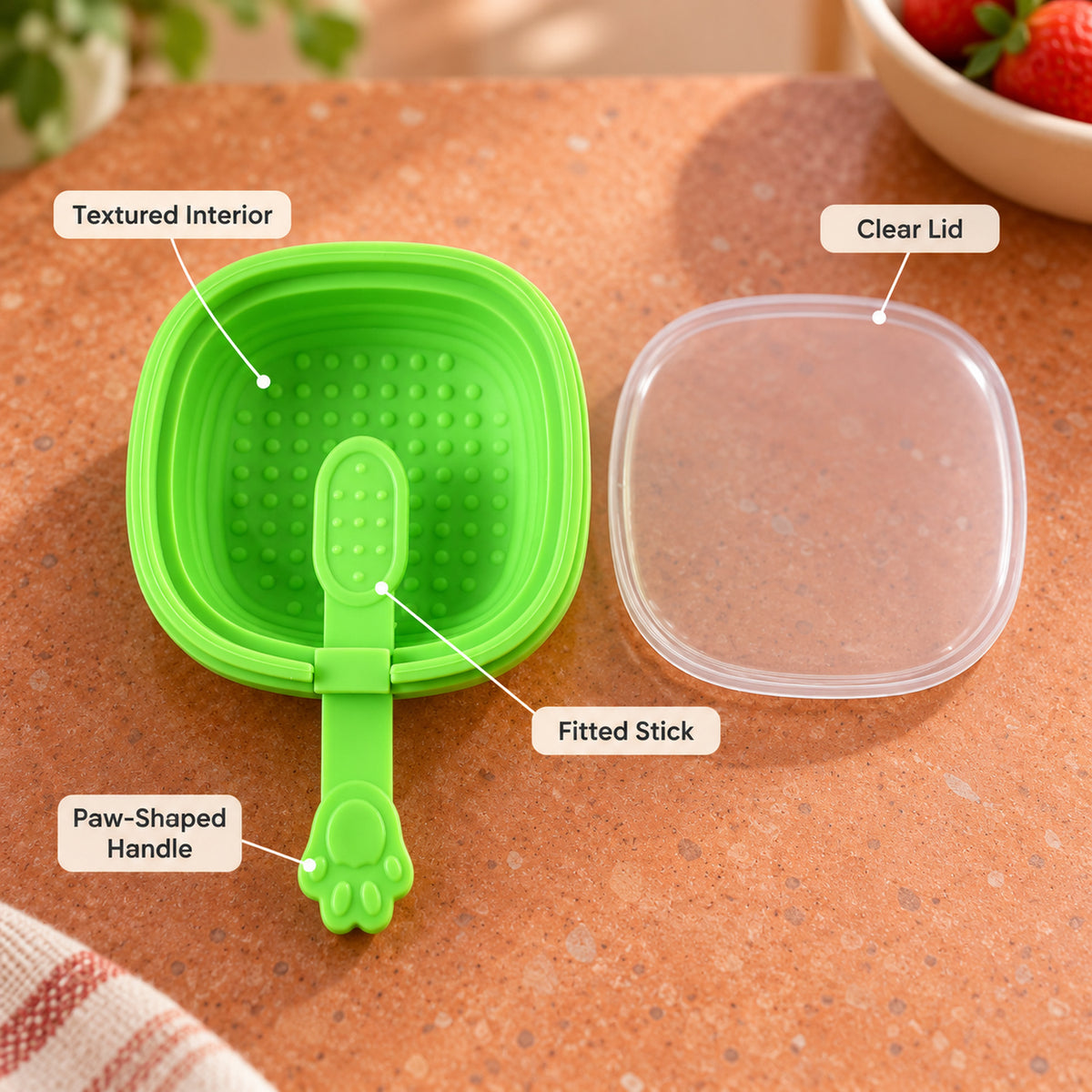 A green silicone mold with a paw handle and clear lid is labeled with its textured interior, fitted stick, and paw-shaped