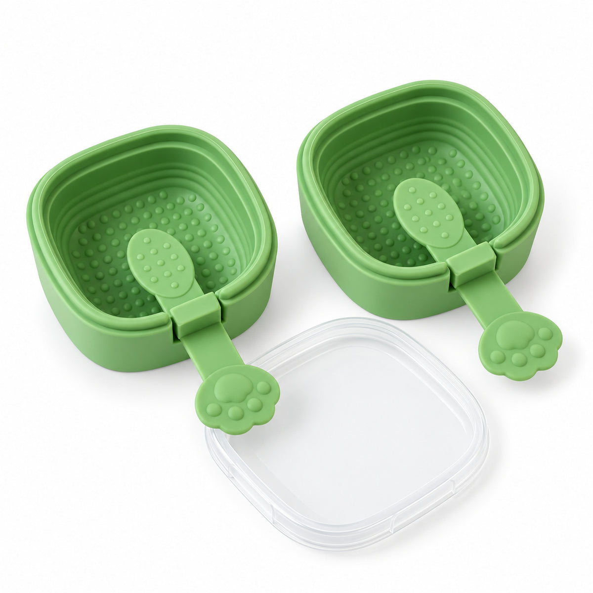 Two empty green square molds with paw-shaped handles and a clear lid are arranged on a white background.