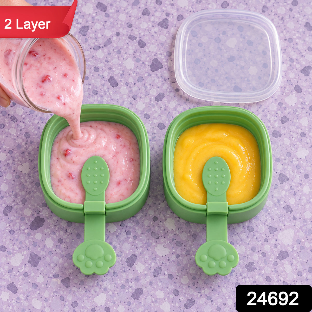 A hand pours pink liquid into a green square mold, beside another mold with yellow liquid, on a purple patterned surface.
