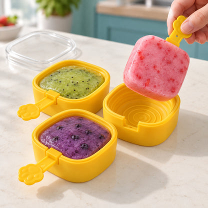 A person removing a pink fruit popsicle from a yellow mold, with two other molds filled with fruit purees.