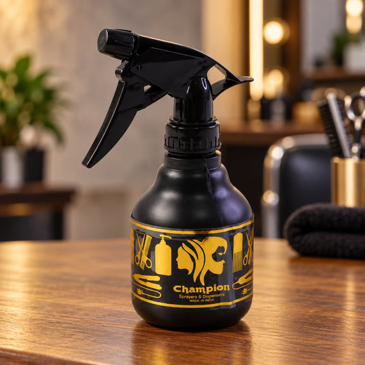 A black plastic spray bottle with a gold label featuring hair styling tools sits on a wooden counter.