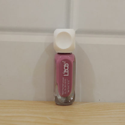 Hand holding mauve rose colour nail polish bottle during manicure