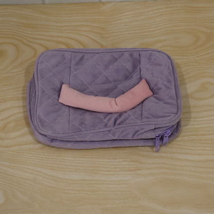 A closed lavender quilted corduroy cosmetic bag with a pink handle and a pink and green tulip applique, shown from a