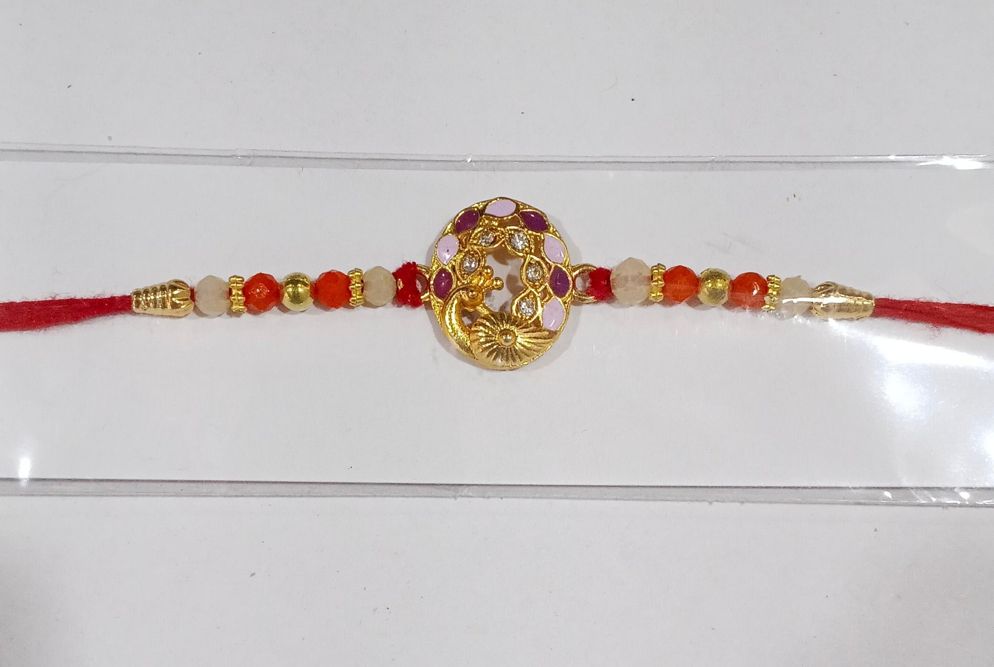 Peacock design rakhi with multicolor beads on white background