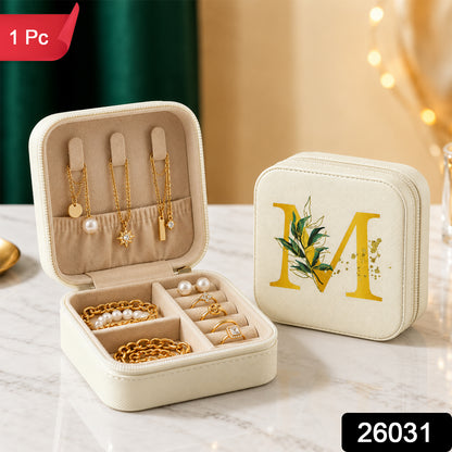 Two beige jewellery boxes, one open with accessories and one closed with a gold 'M', are displayed on a marble surface.