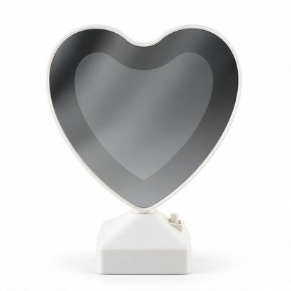 A heart-shaped mirror on a white base, reflecting a dark, subtle image, against a plain white background.