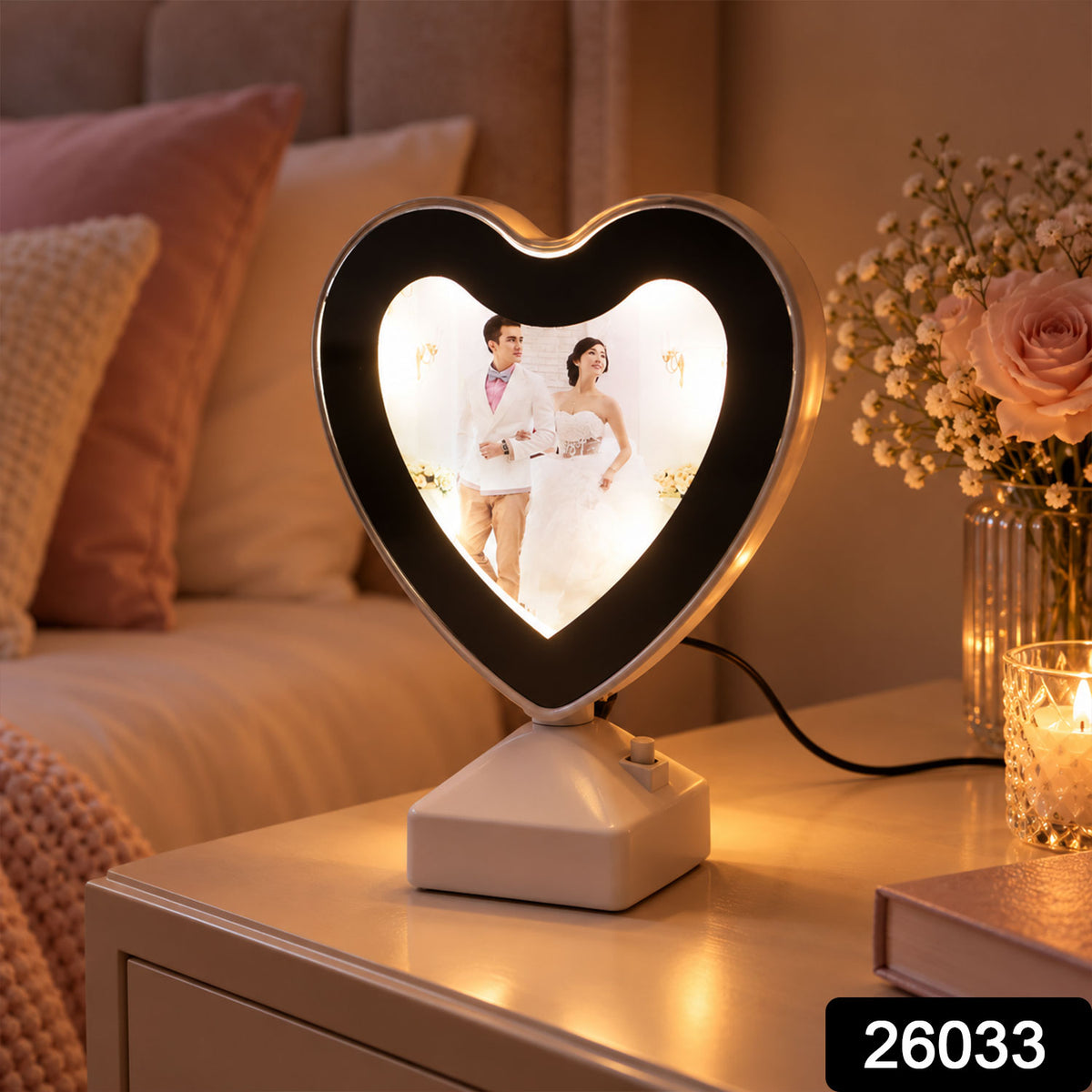 A heart-shaped LED mirror photo frame with a wedding photo, glowing warmly on a bedside table next to flowers. – view 2