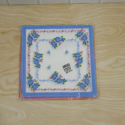 A stack of colorful floral handkerchiefs, with the top one featuring a blue border and floral design, still in its clear