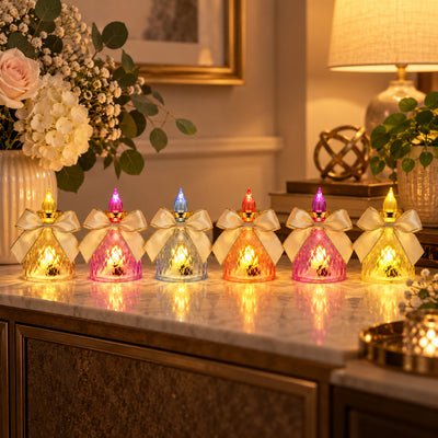 Six colorful LED flameless candles with bows illuminate a marble surface next to a white vase with flowers.