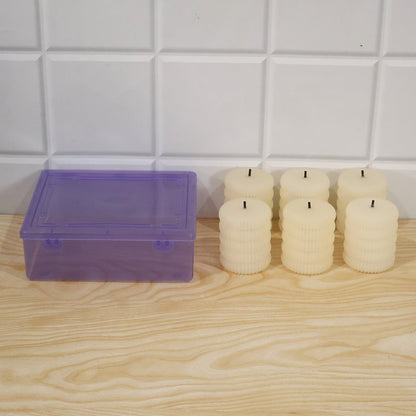 Six unlit cream-colored ribbed flameless LED tealight candles next to a translucent purple storage box.