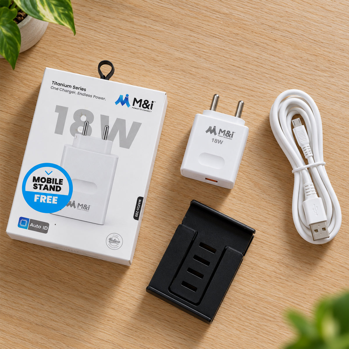 White 18W power adapter, coiled USB-A to Micro USB cable, black mobile stand, and product box on a wooden surface.