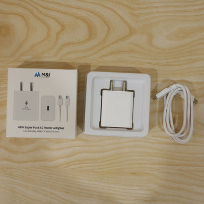 The white charger, its box, and a coiled white USB-C cable on a light wooden background.