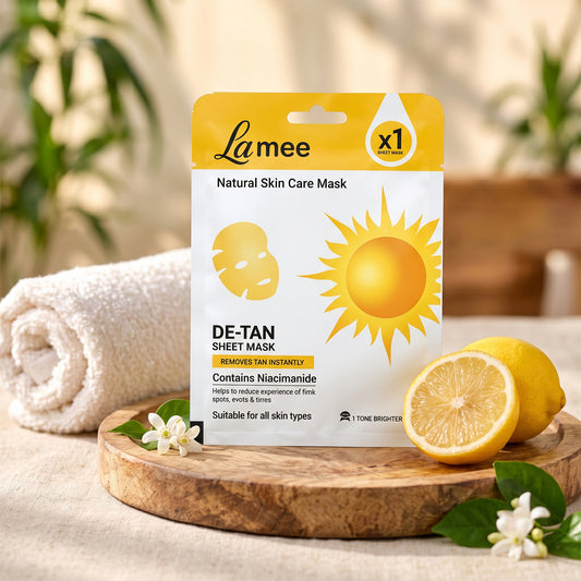 White and yellow sheet mask package with sun and face icons, lemons, and a white towel on a wooden tray.