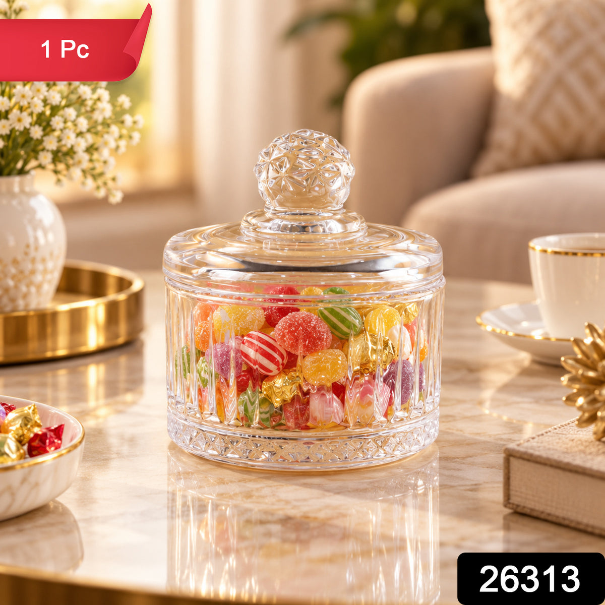 Glass candy bowl with lid, full of various candies, on a table next to a white vase and gold tray.