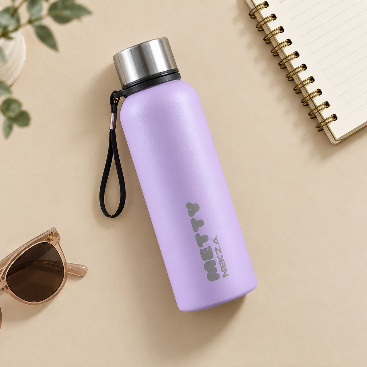 A light purple Metty water bottle with a silver cap and strap rests on a beige surface next to sunglasses and a notebook.