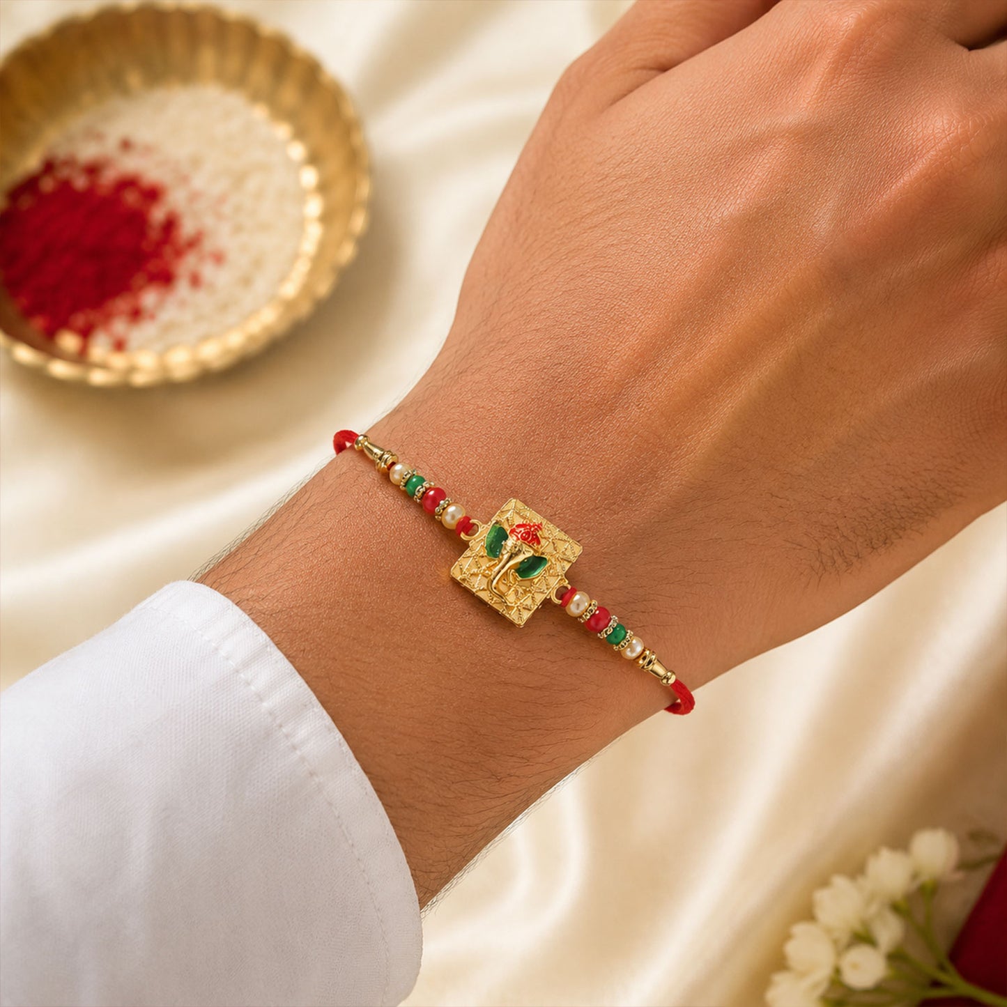 Close up of Golden Ganpati Rakhi showcasing the vibrant red green beads.
