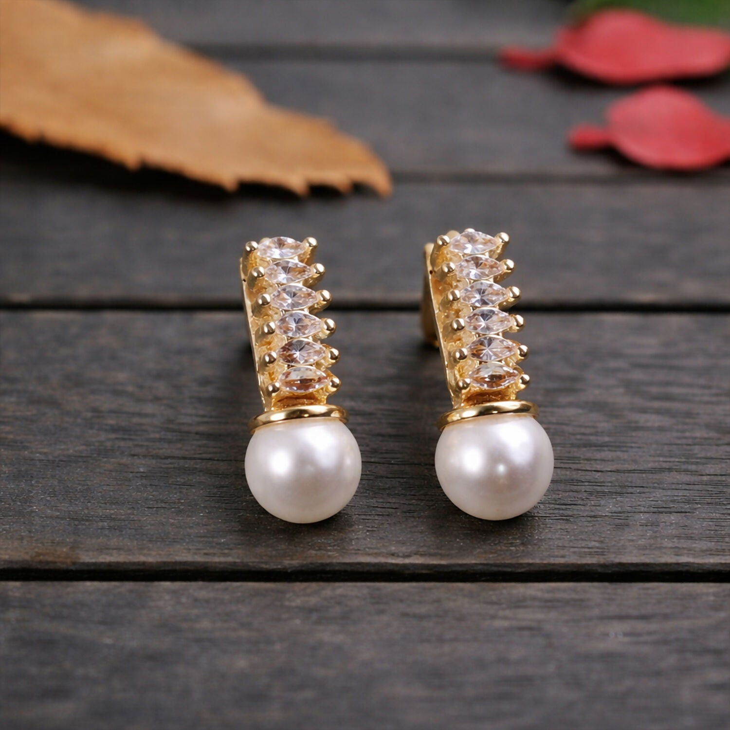 Elegant pearl drop earrings with sparkling stones and gold finish in vertical arrangement