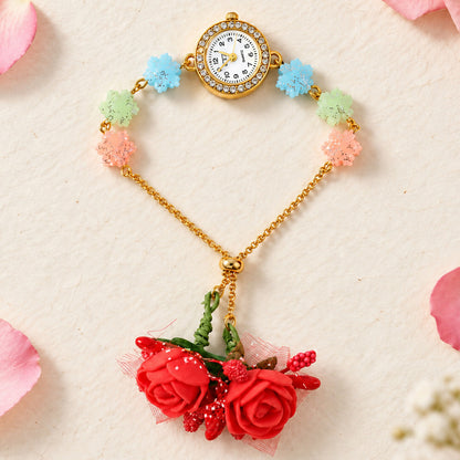 Gold-toned watch with a rhinestone bezel, blue, green, and pink glitter flower links, and red fabric rose charms.