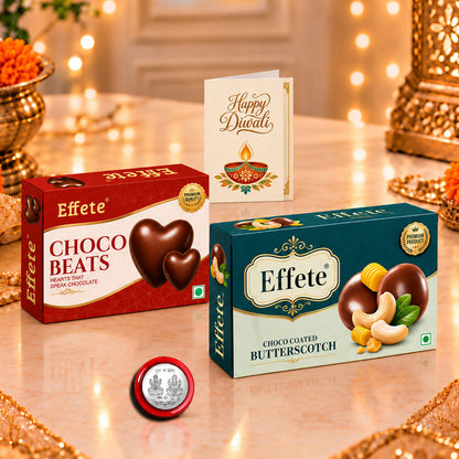 Two Effete chocolate boxes, a silver coin, and a Happy Diwali card on a table with blurred lights.