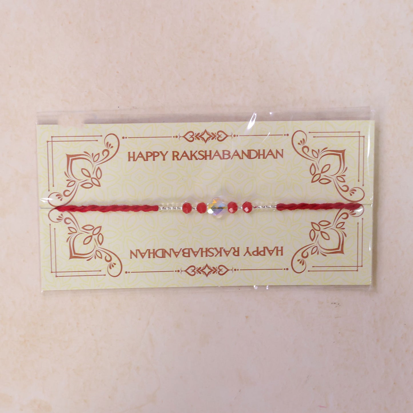 Red Thread Rakhi with Red Beads and an Iridescent Quatrefoil Crystal