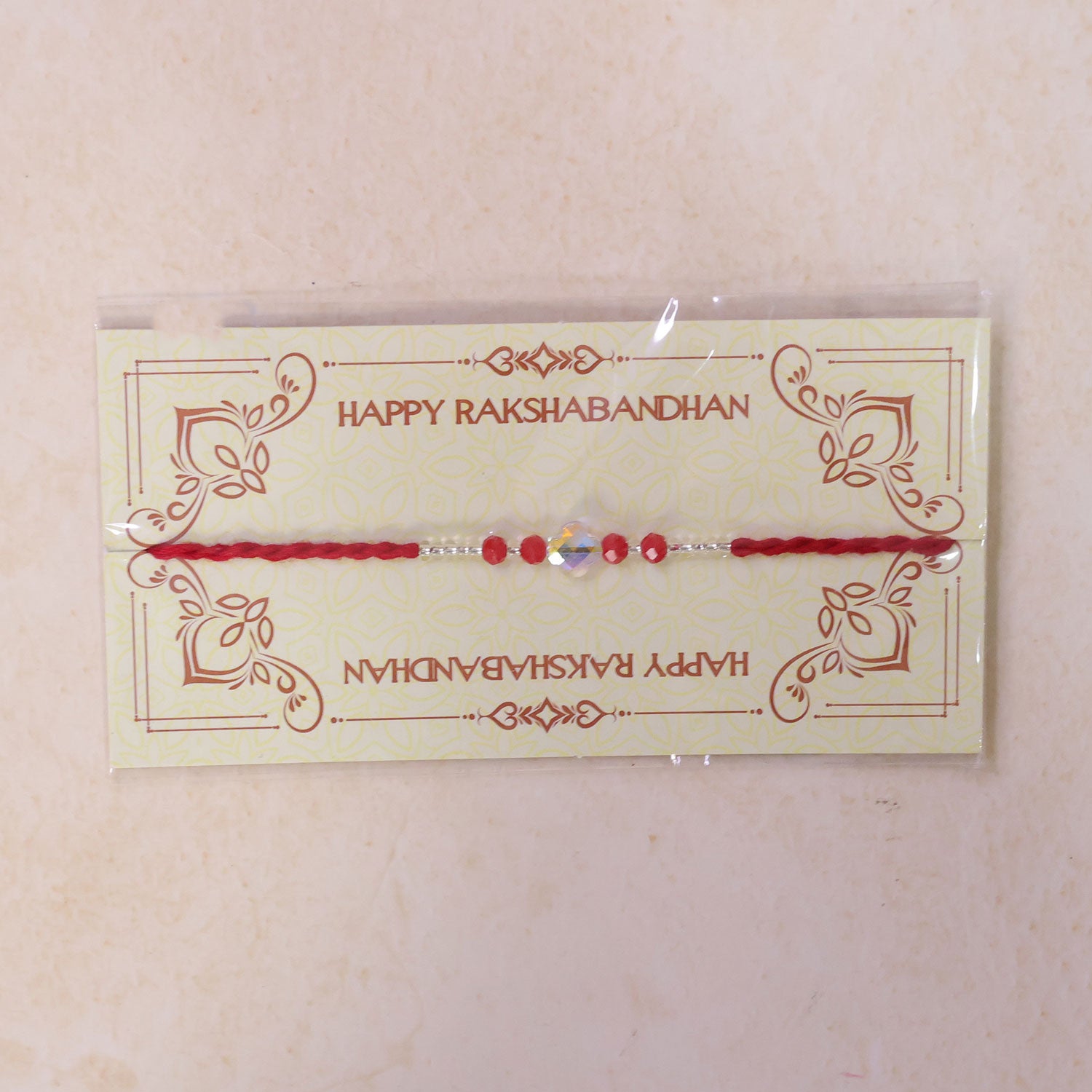 Red Thread Rakhi with Red Beads and an Iridescent Quatrefoil Crystal