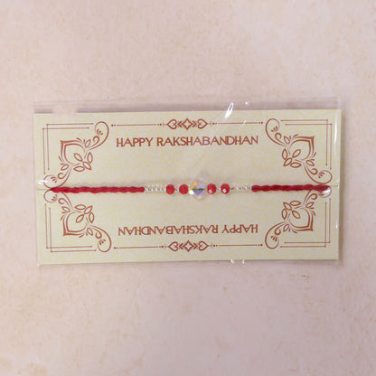 Red Thread Rakhi with Red Beads and an Iridescent Quatrefoil Crystal