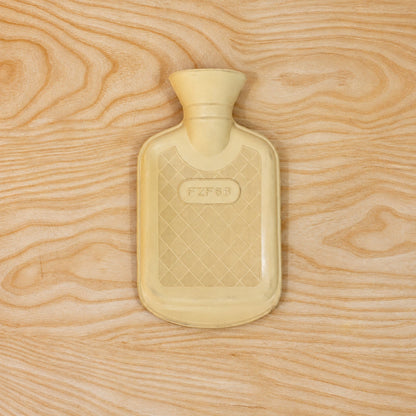 A cream rubber hot water bottle with a textured pattern lies flat on a light wood surface.