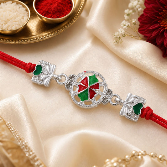 A silver pinwheel charm with red and green enamel, flanked by two silver bow-shaped charms with green hearts, on a red