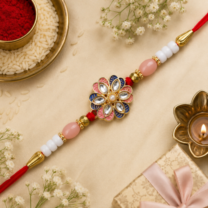 A red thread with pink and white beads, gold accents, and a central floral charm with pink, blue, and clear stones, rests on