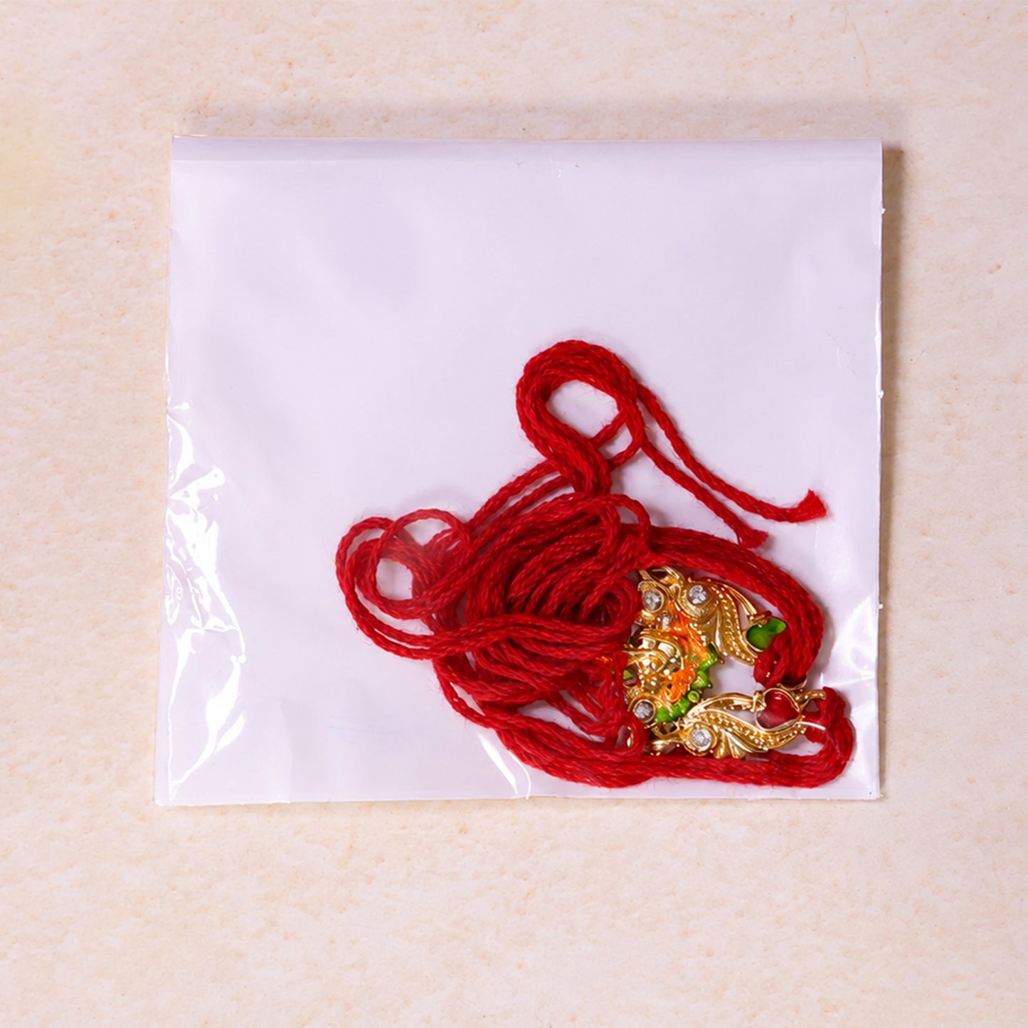 Gold-Toned Lord Ganesha Rakhi with Orange-Green Enamel, Crystal Accents & Red Thread