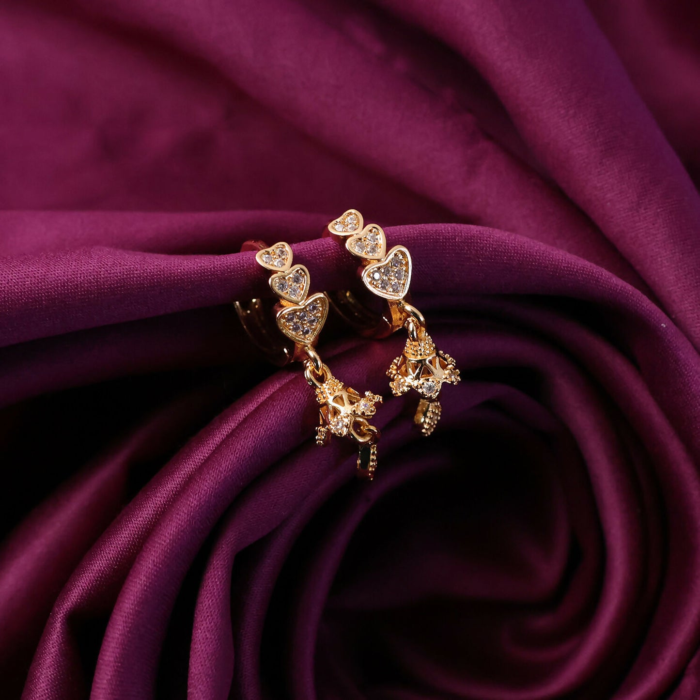 Detailed view of sparkling stone accents on triple heart drop earrings