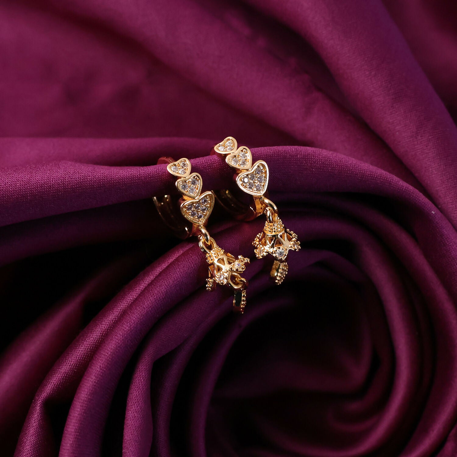 Detailed view of sparkling stone accents on triple heart drop earrings
