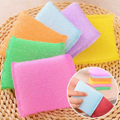 Several colorful scrub sponges in pink, green, orange, light blue, purple, and yellow on a woven surface.
