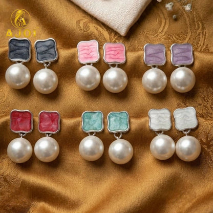 Multiple pairs of pearl drop earrings arranged on surface
